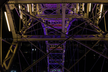 Looking directly through steel girders and poles at other cars on a giant ferris wheel in motion