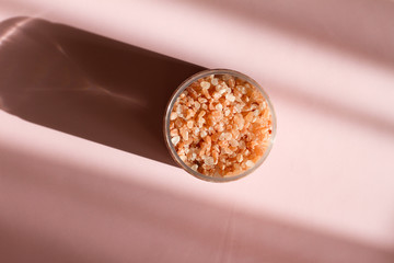 Himalayan salt. Bath salt. Spa treatment. The industry of beauty and relaxation. Scattered salt on a white background. Bath of crystals in a transparent jar. The view from the top. Space for text.