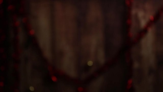 Christmas mood: three lighted candles, one with a big flame in the foreground, red and golden balls, decoupage balls, satin gold ribbon, filmed in low light scrolling from top to bottom