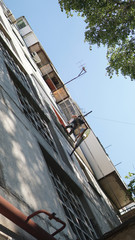 Insulation of the walls of the house. Worker hanging on the ropes