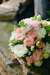 Close up of two golden wedding rings on bridal bouquet of pink and white roses outdoors, copy space. Selective focuse. Wedding concept