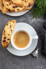 Traditional Christmas pastries, Italian homemade double-baked biscotti or cantuccini cakewith coffee, with nuts and dried fruits. with xmas decorations and fir branches.