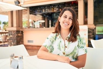 Fototapeta premium Young beautiful woman sitting at restaurant enjoying summer vacation