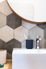 Interior of a house private bathroom. hexagonal Tiles with natural colors on gray brown in a bathroom interior furnishings and supplies majolica laid on the wall near a sink with toothbrush and mirror