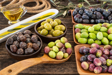 Many types of olive like green & black and olive oil at the rustic wooden table