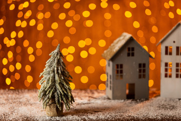 Little fir tree stands next to two gray paper toy houses. Selective focus