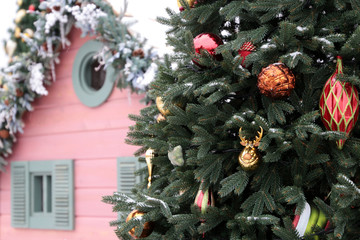 Christmas decorations on a fir branches covered by snow on winter street. New Year tree with toy balls, magic of the holiday