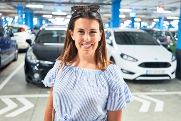 Young woman smiling confident at underground parking lot around cars and lights