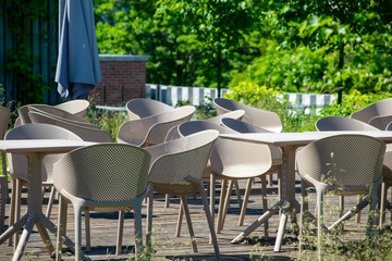 Outdoor restaurant summer terrace - cozy cafe with chairs and tables in the green downtown park.