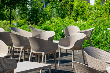 Outdoor restaurant summer terrace - cozy cafe with chairs and tables in the green downtown park.