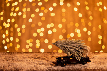 Little model of fir stands on wooden table covered in thin snow. Selective focus