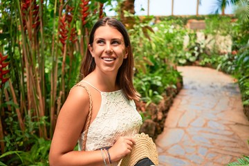 Young beatiful woman smiling happy and cheerful at butterfly garden on a sunny day of summer