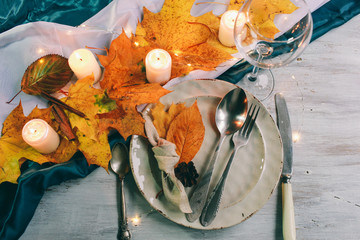 served table with decorations, candles and autumn leaves Table served for autumn dinner in living room
