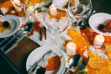 served table with decorations, candles and autumn leaves Table served for autumn dinner in living room
