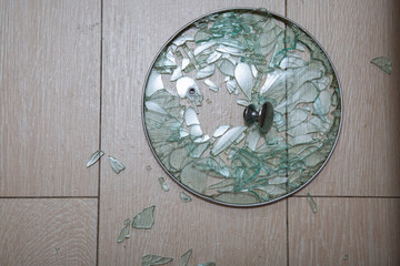 A close-up of a broken glass lid lies on a stake of tile. shards of glass shine. soft focus, top view