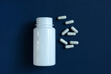 Capsules medication with a jar open in the background