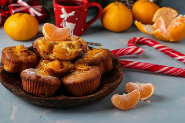 Homemade muffins with tangerines, sprinkled with powdered sugar is located on the New Year's or Christmas light blue background