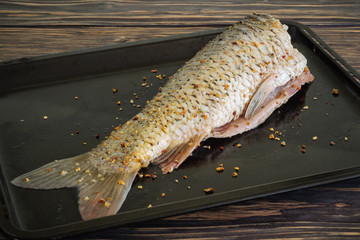 Fresh raw chopped carp grated with spices for baking on a metal baking sheet. side view