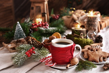 coffee in a cup with red knitted warmer on Christmas table