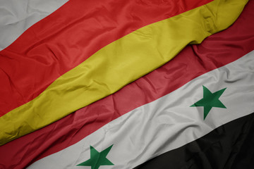 waving colorful flag of syria and national flag of south ossetia.