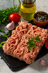 Healthy food, cooking concept. Homemade raw organic minced beef on a black cutting board and ingredients on a table.