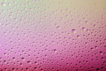 closeup of water droplets on a glass. Rainbow background, colorful abstract pattern.