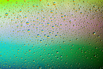 closeup of water droplets on a glass. Rainbow background, colorful abstract pattern.