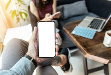 Mockup image blank white screen cell phone.men hand holding texting using mobile on desk at home office. background empty space for advertise text.people contact marketing business and technology 