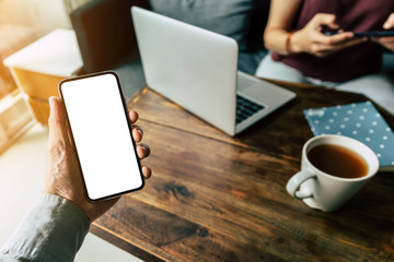 Mockup image blank white screen cell phone.men hand holding texting using mobile on desk at home office. background empty space for advertise text.people contact marketing business and technology 