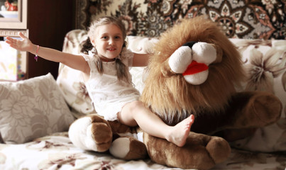 cute little girl playing with a big soft toy sitting on a couch