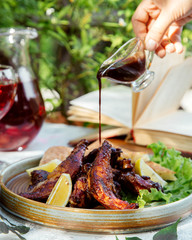 man pouring nar-sharab pomegranate sauce on the grilled chicken served with lemon