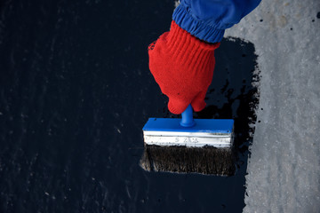 Worker applies bitumen mastic on the foundation