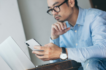 hand holding using texting cell phone and typing computer.businessman at workplace Thinking investment plan.chatting contact Investor.searching for information use internet.connecting people concept