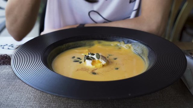 Woman eating pumpkin cream soup at restaurant