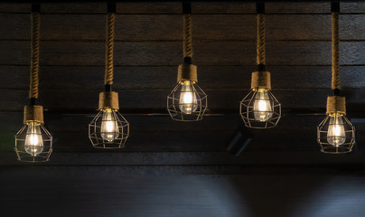 Fototapeta na wymiar Modern ceiling lights bulbs lamp made of brass wire frame and rope interior retro and loft style decorating with brown wooden wall