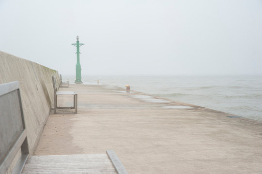 Seaport entrance with breakwater and navigational lights on a foggy day. Baltic sea, Rowy, Poland