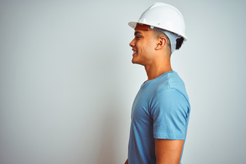 Young brazilian engineer man wearing security helmet standing over isolated white background...