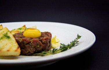 beef tartare with croutons on black background