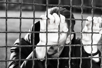 Hands of the prisoner on a steel lattice close up