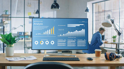 Shot of a Desktop Computer in the Creative Modern Office. Monitor Screen Shows Company Growth Data...