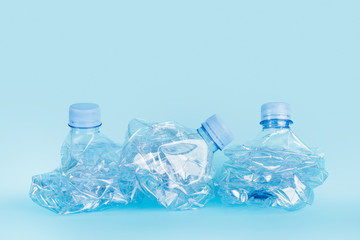 Botellas de plástico arrugadas sobre fondo celeste aislado. Vista de frente. Concepto: Medio ambiente. Reciclado. Copy space