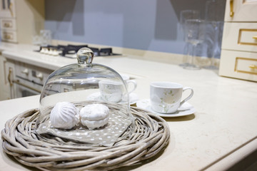 Classic elecant glass cover for desserts with two sweet marshmallows on the wicker plate. Close up photo in the luxury interior.