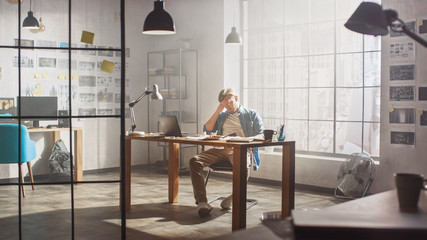 Frustrated and Tired Young Creative Designer Works on Laptop at His Desk. He is Feeling Anger and Dissatisfaction, Showing Facepalm.