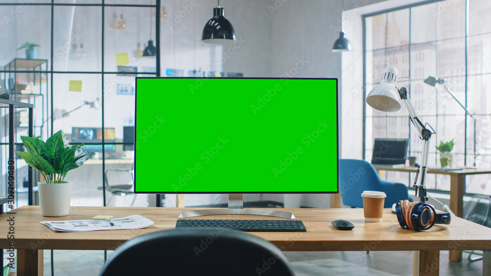 Poster Wide Green Mock-up Screen Desktop Computer Standing on the Desk in the Modern Creative Office. In the Background Bright Creative Loft for Developers and Designers where Professional Working.