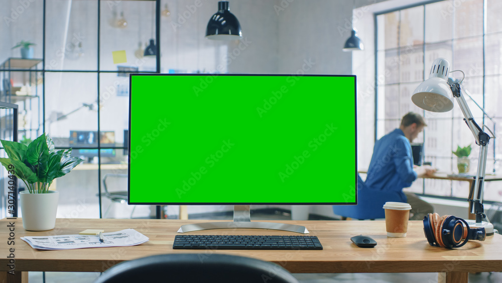 Poster Wide Green Mock-up Screen Desktop Computer Standing on the Desk in Modern Creative Office. In Background High Ceiling Creative Loft for Developers and Designers where Professional Working at his Desk.