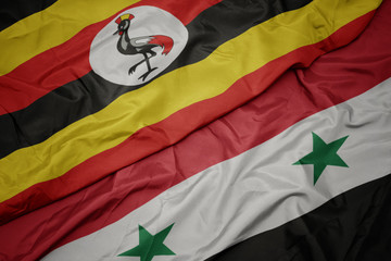 waving colorful flag of syria and national flag of uganda.