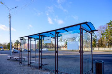 Photo of an empty public transport stop on a city street on a sunny clear day.