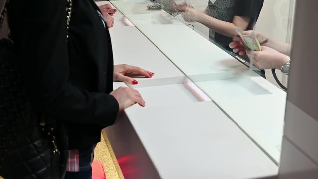 Employee and client count money on a counter at the currency exchange office. Female hand with money in cash department window.