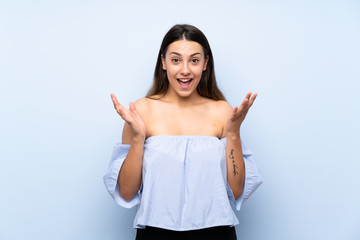 Young brunette woman over isolated blue background with surprise facial expression