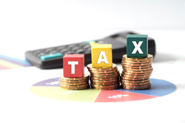 Taxiation concept with wooden block, calculator and stacked gold coins